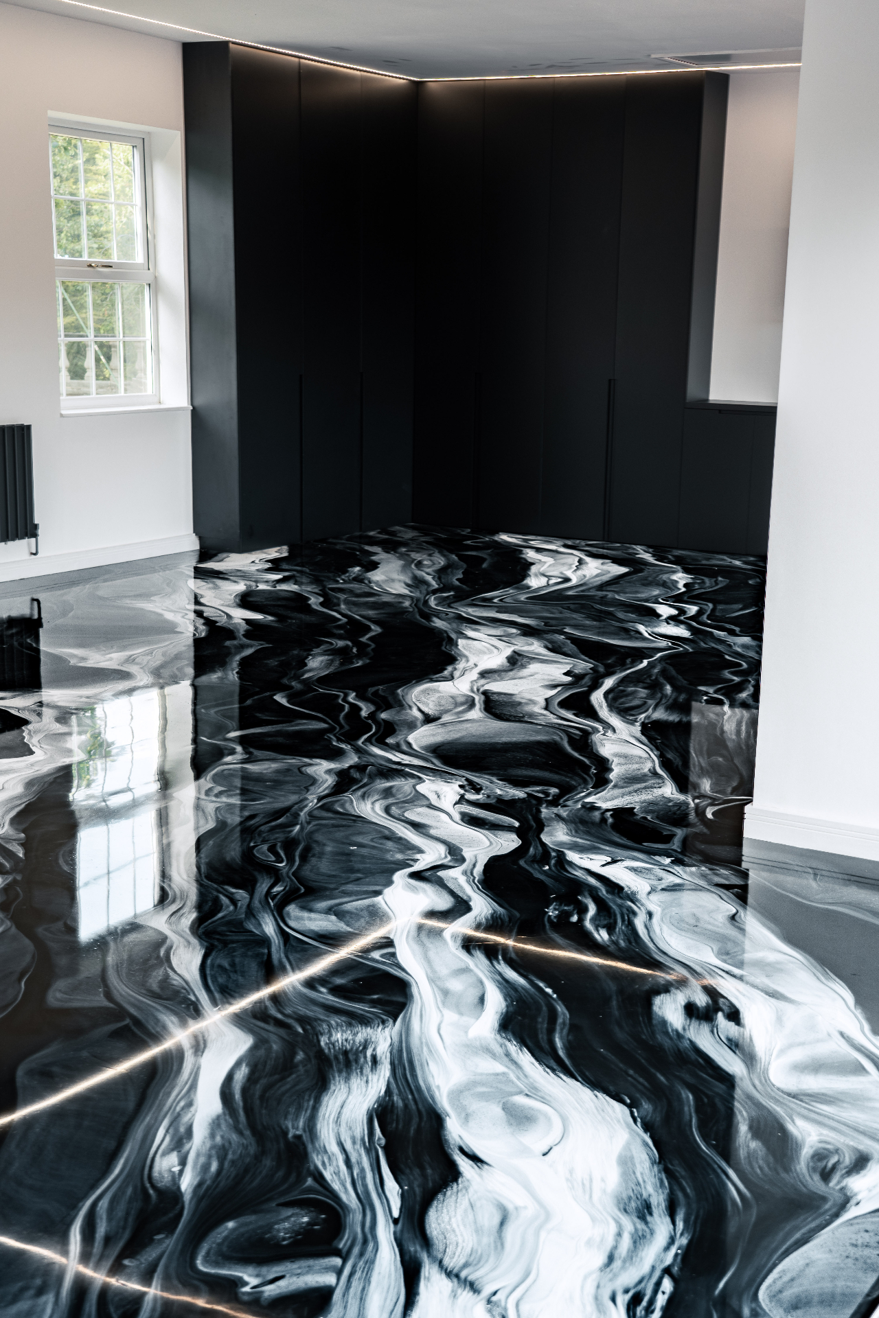 Auto Marble black metallic resin floor in residential garage with dark cabinetry and reflective swirl finish