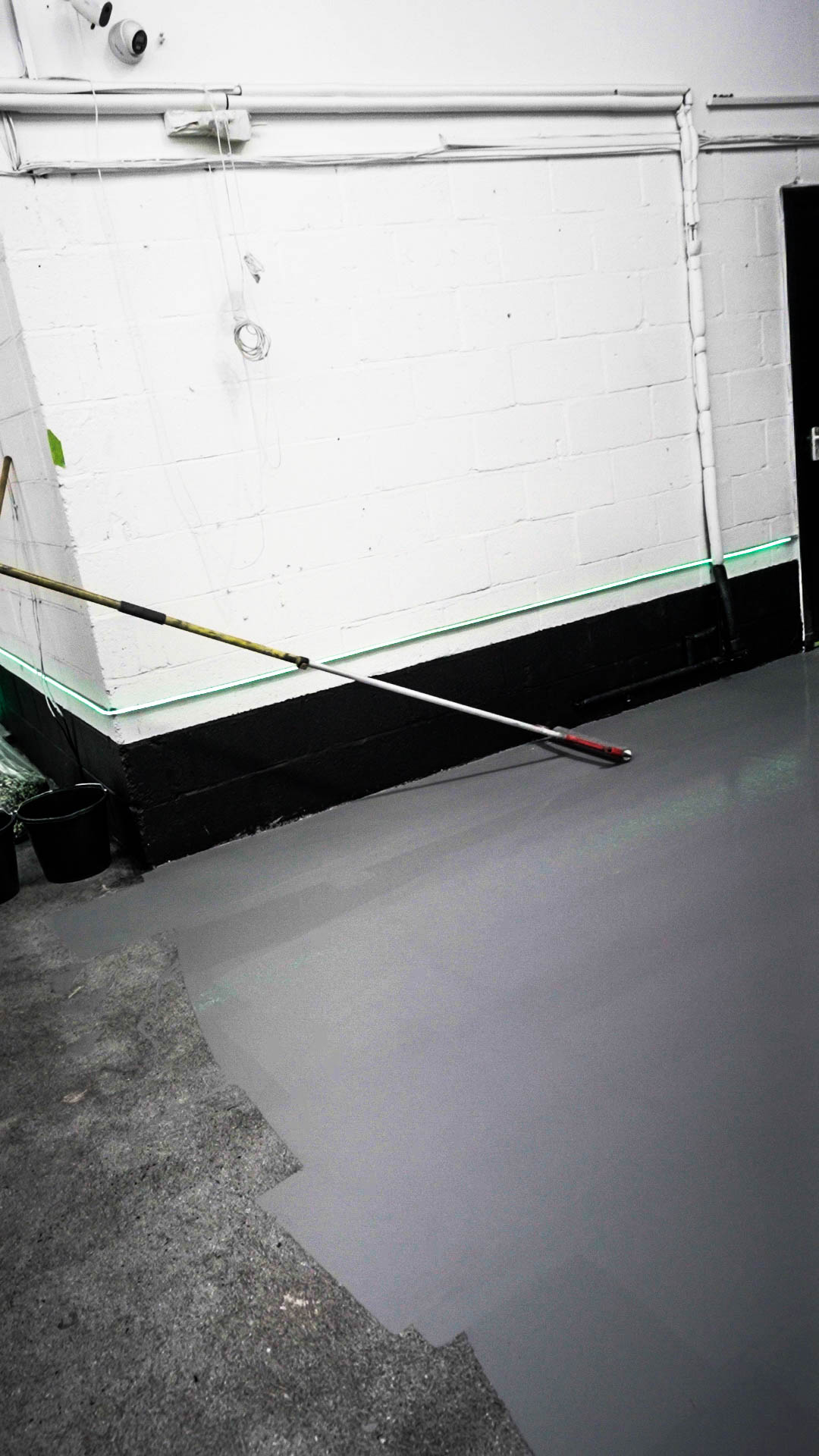 epoxy resin being poured and rolled onto commercial workshop floor surface