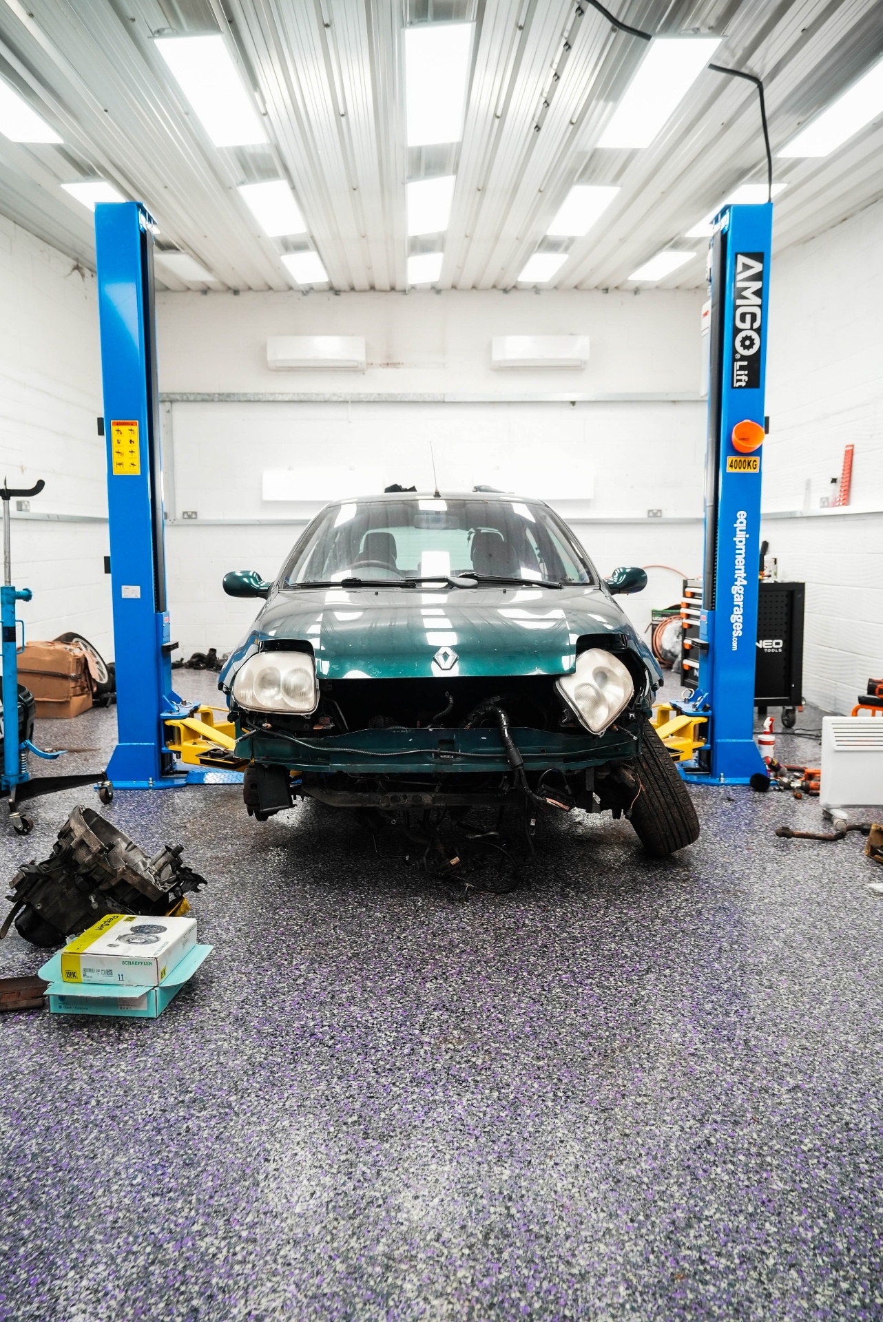 Auto Flake resin garage floor front view with car elevated on hydraulic lift