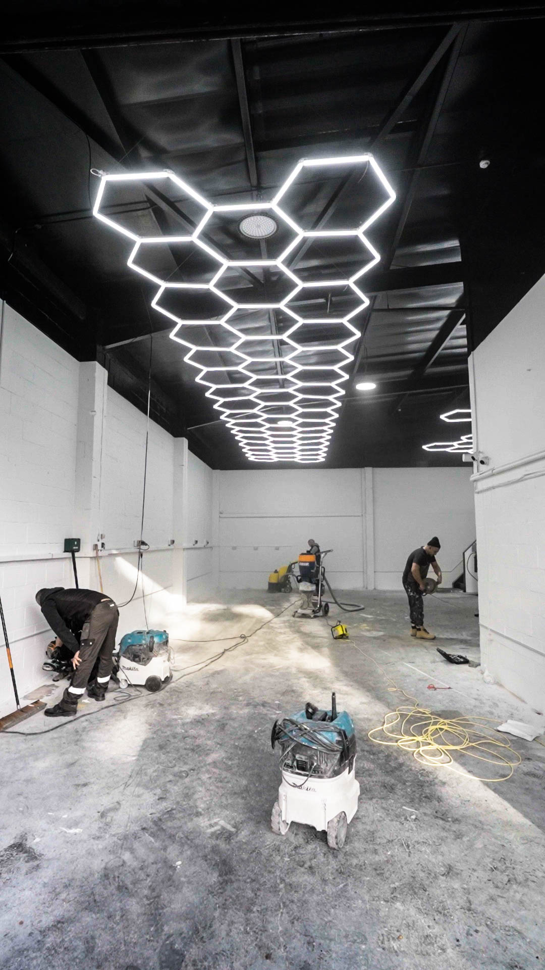 concrete floor preparation under hexagonal LED lighting in commercial workshop unit