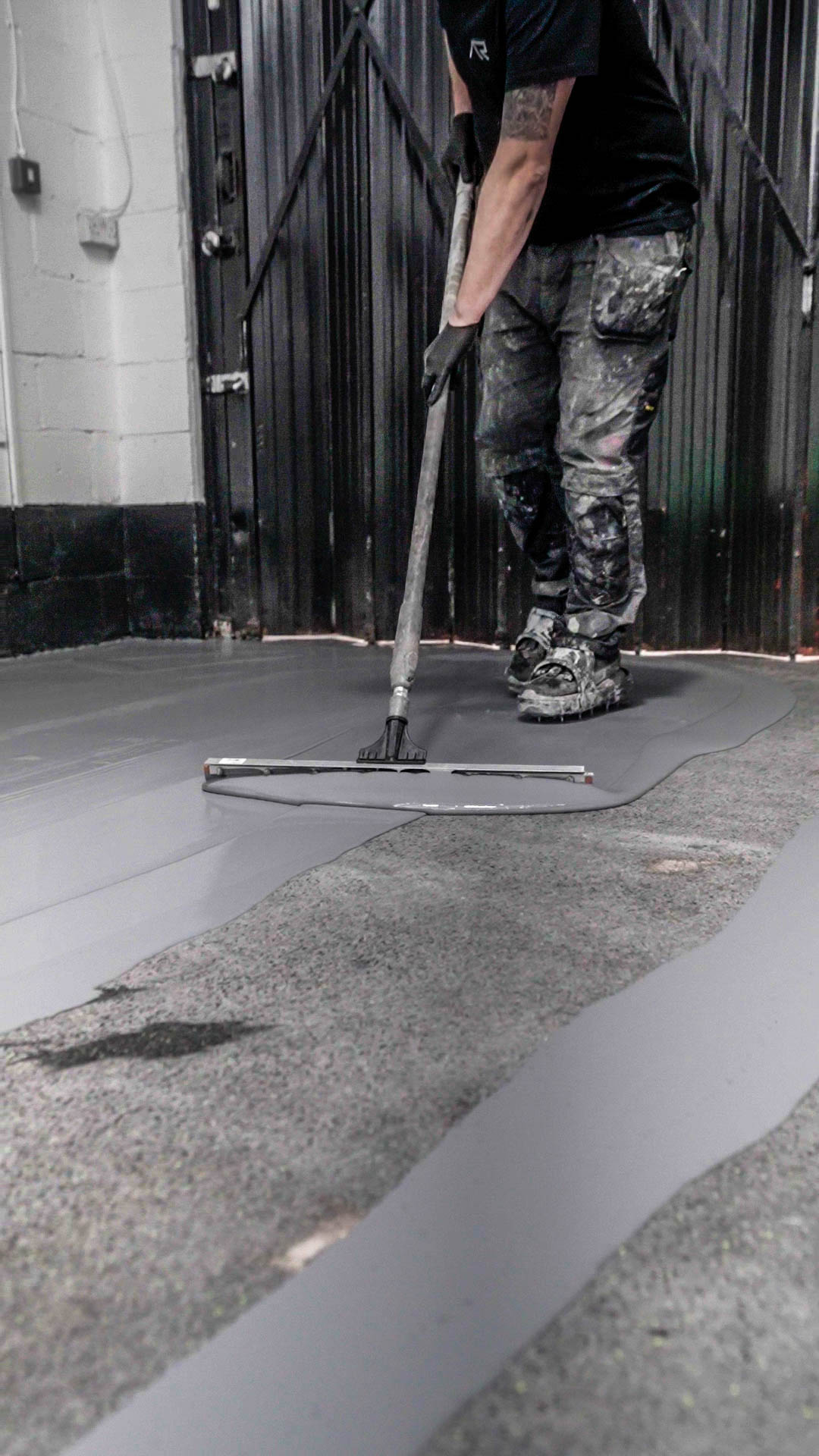 AutoResin technician applying epoxy resin with squeegee across commercial concrete floor